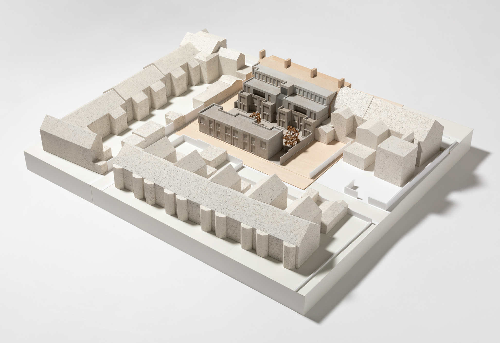1:100 scale architectural model of the proposed Moseley Passage development, showing the mews courtyard, adjoining retained building, surrounding streetscape, and landscape setting. The proposal is distinguished from the wider context through contrasting materials and finishes, with trees and public realm features represented throughout the model.