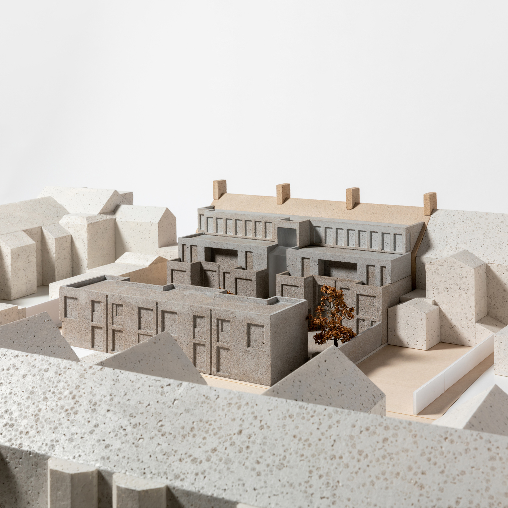 1:100 scale architectural model of the proposed Moseley Passage development, showing the mews courtyard, adjoining retained building, surrounding streetscape, and landscape setting. The proposal is distinguished from the wider context through contrasting materials and finishes, with trees and public realm features represented throughout the model.